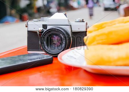 Old Vintage Analogue Camera on the Table with Phone and Youtiao
