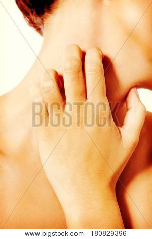 Topless woman scratching her neck.