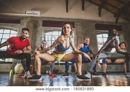 Multi-ethnic group of people training in a gym - Personal trainer and sportive persons in a fitness class