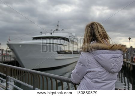 Woman watching at the yacht in the bay