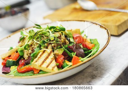 Delicious vegetarian salad with tofu, kinoa and vegetables. A plate of tasty and healthy food - vitamins and health. Soft focus.
