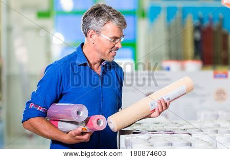 Dad choosing wallpapers for girls room in home improvement store