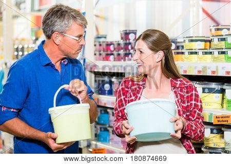 Home improvement couple, woman and man, in hardware store arguing about color of paint for renovating