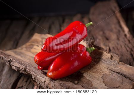 Red chilly pepper on wooden black background. Red hot chili peppers. Domestic cultivation extra hot chilli burn.