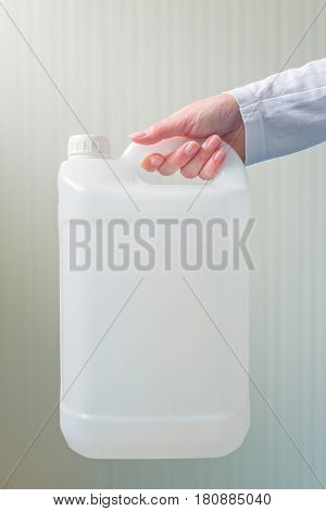 White unlabeled plastic 5 liters tank canister in female hand chemistry and chemical liquids mock-up container