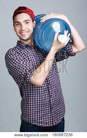 Water delivery. Cheerful young deliveryman holding a water