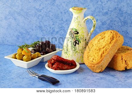 A set of dishes of greek cuisine: olives, sun dried tomatoes, lemon, beetroot, jar with olive oil and traditional dry bread. Traditional Greek food. Mediterranean lifestyle.