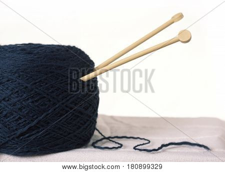 Ball of dark blue woolen yarn knitting needles. White background