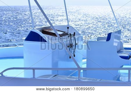 White sailing boat or yacht with steering wheel on steering stand in blue sea or ocean water on sunny day on seascape background. Idyllic summer vacation. Transport and traveling