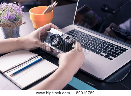 Art Graphic designer and photographer working desk with vintage camera notebook laptop in vitnage tone