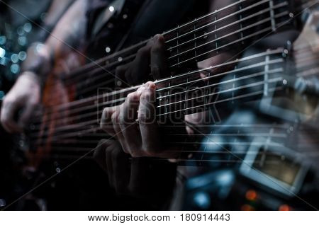 Guitar neck close-up on a concert of rock music in the hands of a musician. Double exposure