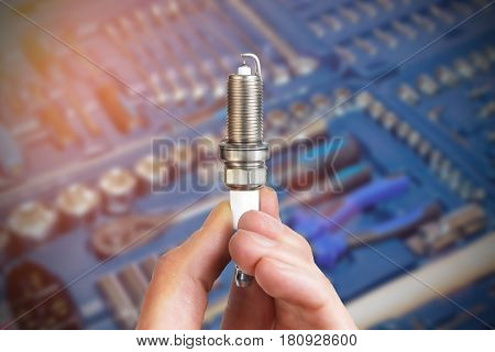 Mechanic holds a spare part spark plug in his hand. Auto part spark plug close-up.