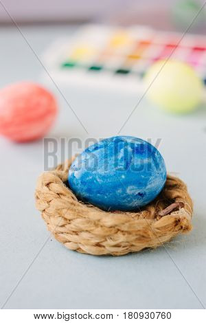 Deep Blue Easter Egg On Nest Over Bright Background.