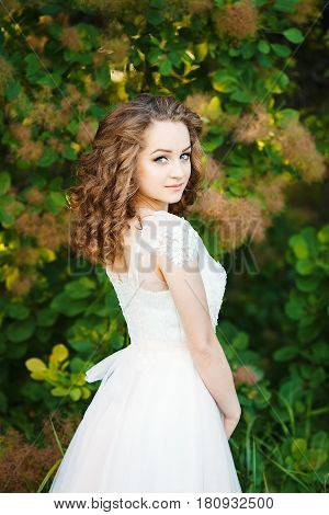 Portrait of young sexy girl. She has curly hair and dressed in a white dress
