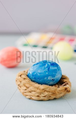 Deep Blue Easter Egg On Nest Over Bright Background.