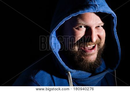 Solid bearded middle-aged man in a hood emotional portrait on black background