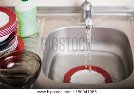Cleaning dishware kitchen sink sponge washing dish. Close up of female hands in yellow protective rubber gloves washing