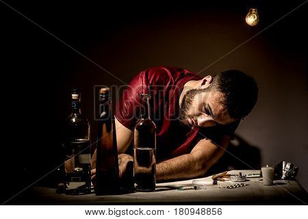 Young man with beard lost in the vices of alcoholism smoking and drug addiction