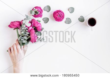 Modern spring design with bright pink flowers in hand on white desk background top view moke up