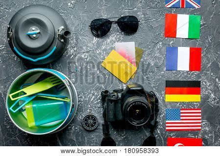 traveller lifestyle items with compass and plactic dishes on gray table background top view