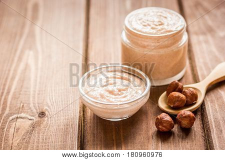 organic cosmetic for women body care with natural huzelnut scrub on desk background