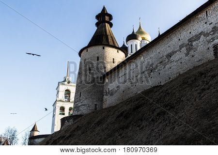 The ancient Russian city of Pskov. Fortress wall and limestone tower. Belfry and domes of the Cathedral of the Holy Trinity.