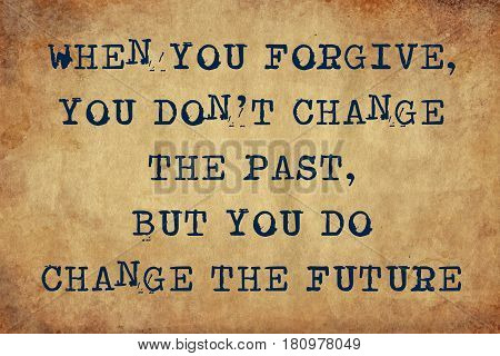 Inspiring motivation quote of when you forgive, you don't change the past, but you do change the future with typewriter text. Distressed Old Paper with Typing image.