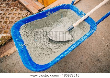 Blue clean new wheelbarrow for cement. Laying the first shovel cement in the foundation on the construction of the house.