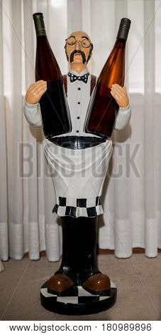 Wine holder doll holding two bottles of wine