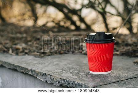 Red Cup of delicious coffee to go on a blurry background