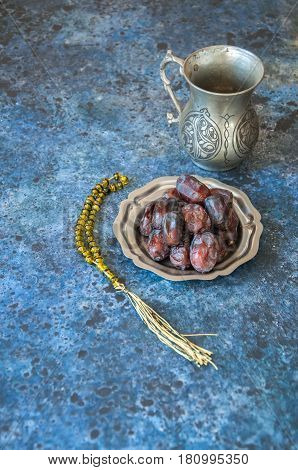 Dried Date Fruits Or Kurma Served On A Old Vintage Palte With Ornaments And Beads On A Blue Stone Ba