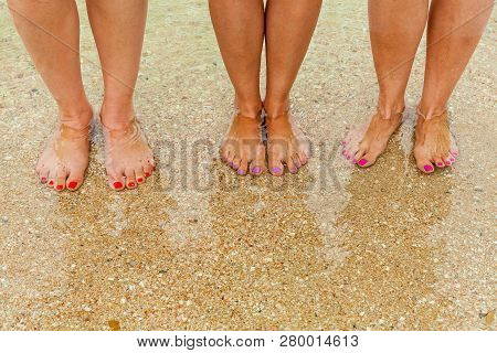 Female Legs With Multi-colored Nails On The Seabed Are Visible Through The Crystal Clear Water. Fema