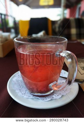 Cup With Red Fruit Tea Is On Table In Restaurant.