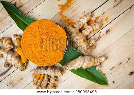 Turmeric Powder And Fresh Turmeric (curcuma) In Black Bowls On Old Wooden Table. Herbal