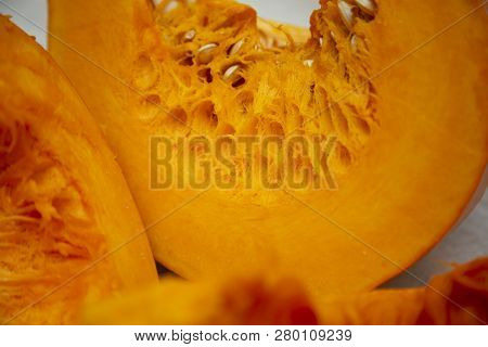 Slices Of Tasty And Healthy Vegetables - Juicy Bright And Orange Pumpkin With Seeds On The Table.