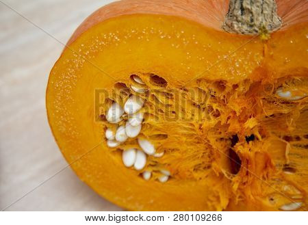 Half A Juicy Bright And Ripe Pumpkin In The Cut With A Stem And Seeds Of White. Pumpkin Oval-shaped 