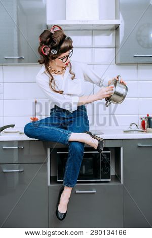 A portrait of a beautiful girl wearing everyday clothes and doing washing up. Fashion home shot. Pin-up style.