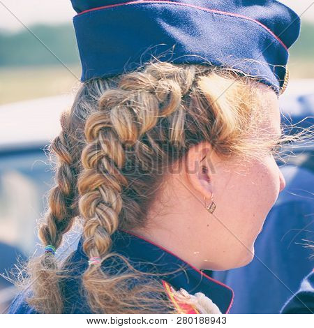 Woman With Pigtails In Uniform In A Forage-cap. Rear View