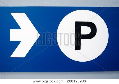 Blue Parking Sign With White Arrow And Black Capital P On White Background