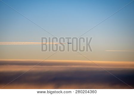 Condensation Trails Behind Airplane In High Altitude Glowing In Sunlight