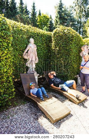 Dobrzyca, Poland - August 6, 2018: Boy And Man Laying On Sun Beds Close By A Shrub At The Hortulus P
