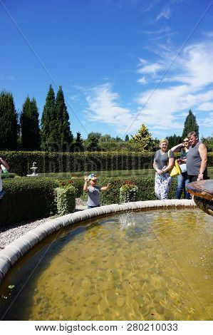 Dobrzyca, Poland - August 6, 2018: People Standing By A Water Fountain On The Hortulus Park In The S