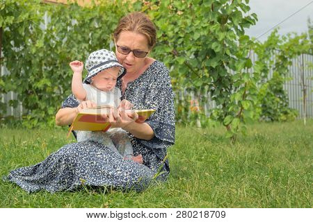Woman With Child. Working Woman With Child. Reading The Book And Playing With Baby. Grandmother With