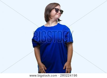 Young adult woman with down syndrome wearing sunglasses over isolated background looking away to side with smile on face, natural expression. Laughing confident.