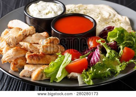 Delicious Mediterranean Shawarma Plate With Chicken, Hummus, Salad And Sauces Close-up Table. Horizo