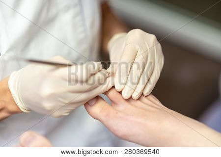 Closeup View Of Pedicurist Making Medical Pedicure Removing Cuticle Wearing Protective Gloves.