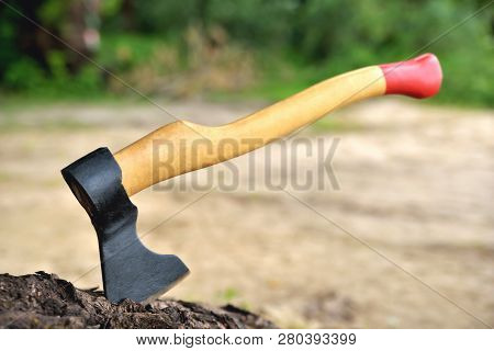 A Beautiful-shaped Ax Sticks Out In A Tree, With A Yellow Handle Close-up, On A Natural Background