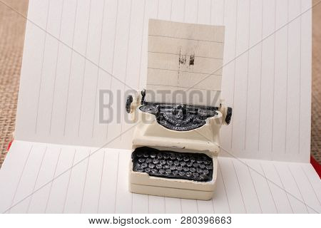 Retro Syled Tiny Typewriter Model On A Paper Background