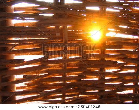 Wicker Strawy Wall With Rifts And A Sunlight Coming Through It. Evening, Sunset.