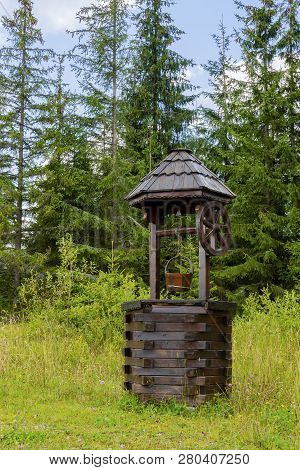 A Wooden Well Located On The Margins Of A Fir Forest, In A Rural Region Of Romania